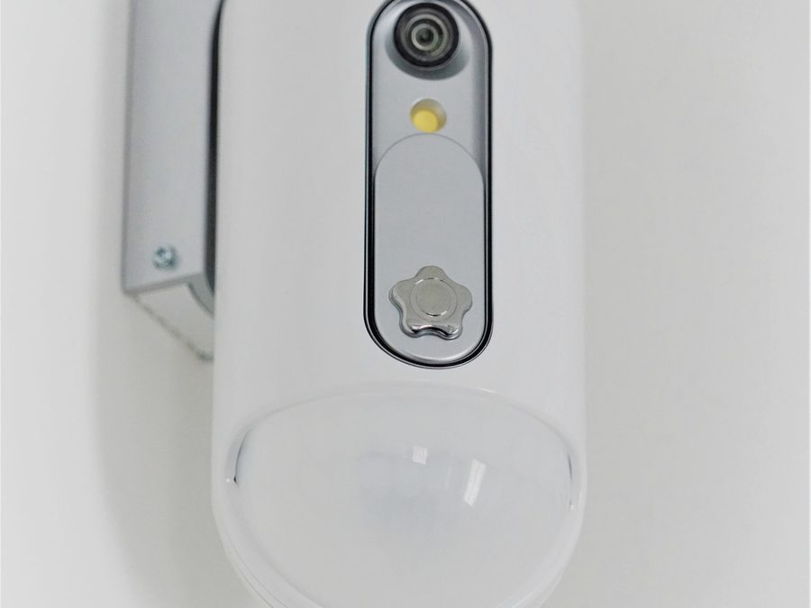 Detector de presença branco com câmera acoplada, montado em canto de parede